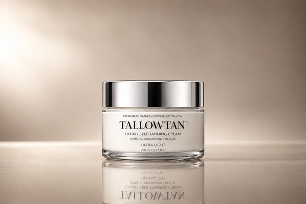 A glass jar of Tallowan Luxury Self-Tanning Cream with a reflective silver lid, set against a warm beige gradient background with a soft reflection below.